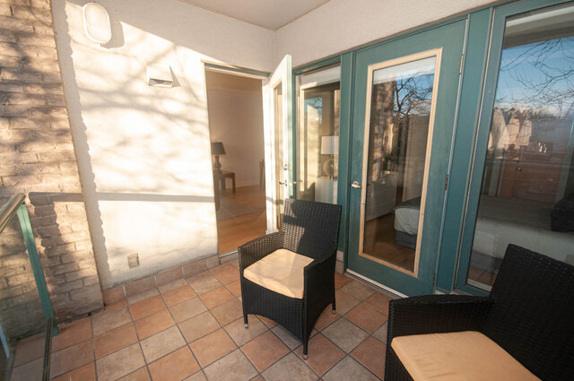 Spacious patio with tiled flooring, wicker furniture, and sliding glass doors leading to the interior.
