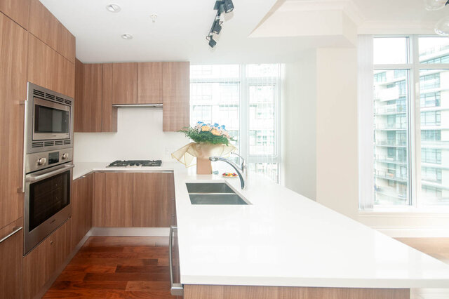 Bright kitchen with white countertops, hardwood floors, and a city view. - 912 - 175 Victory Ship Way, North Vancouver