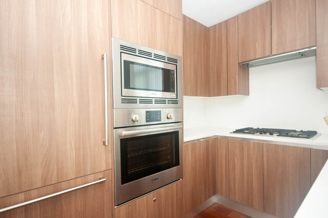 Bright kitchen with modern stainless steel appliances, light wood cabinets, and white countertops. - 912 - 175 Victory Ship Way, North Vancouver