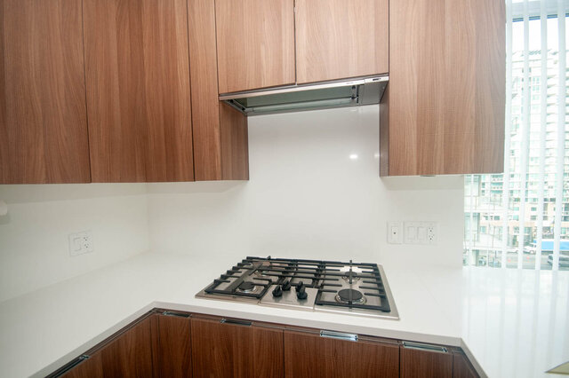 Bright kitchen with modern gas stove, sleek white countertops, and wooden cabinetry. - 912 - 175 Victory Ship Way, North Vancouver
