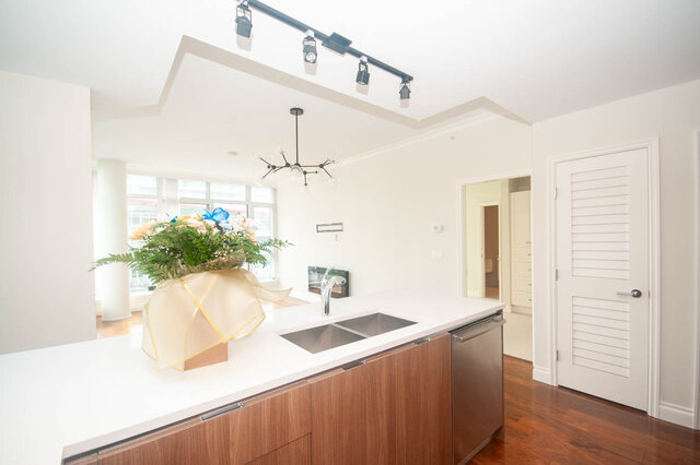 Bright kitchen with modern island, hardwood floors, and a sleek chandelier. - 912 - 175 Victory Ship Way, North Vancouver