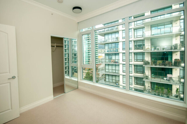 Spacious bedroom with large windows offering a stunning city view. - 912 - 175 Victory Ship Way, North Vancouver