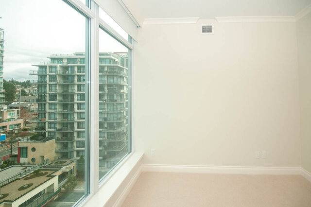 Spacious living room with large windows offering a stunning city view. - 912 - 175 Victory Ship Way, North Vancouver