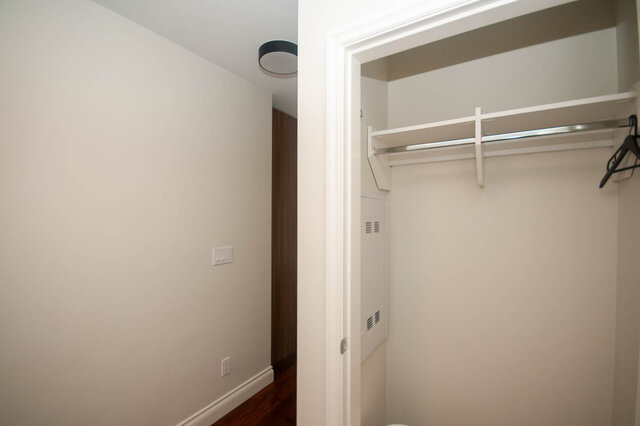Spacious walk-in closet with white shelves and a hanger, clean and organized. - 912 - 175 Victory Ship Way, North Vancouver