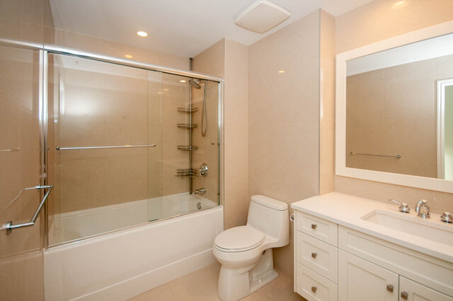 Spacious bathroom with dual vanities, a walk-in shower, and beige tiles. - 912 - 175 Victory Ship Way, North Vancouver