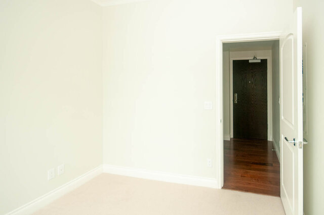 Spacious bedroom with hardwood floating shelves and a cozy carpeted floor. - 912 - 175 Victory Ship Way, North Vancouver