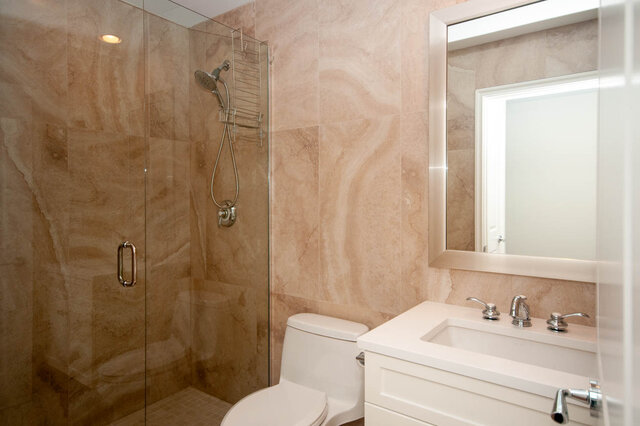 Spacious bathroom with marble walls, glass shower, and modern sink. - 912 - 175 Victory Ship Way, North Vancouver