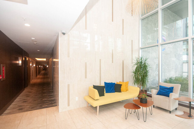 Spacious living room with modern furniture, large windows, and a cozy corner. - 912 - 175 Victory Ship Way, North Vancouver