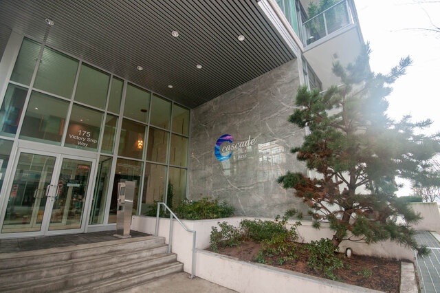 Modern 2-bedroom condo entrance with sleek glass doors and marble wall. - 912 - 175 Victory Ship Way, North Vancouver