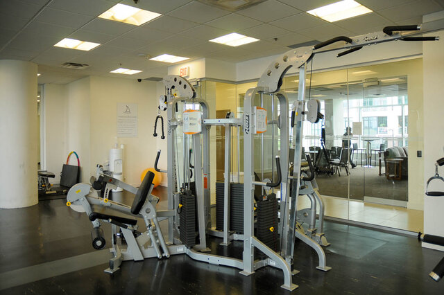 Spacious fitness room with modern equipment and large mirrors, ideal for workouts. - 912 - 175 Victory Ship Way, North Vancouver