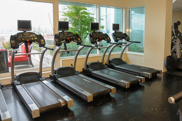 Spacious fitness room with four treadmills and a city view. - 912 - 175 Victory Ship Way, North Vancouver