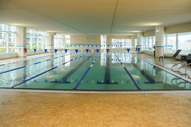 Spacious indoor pool with lane dividers and large windows offering a city view. - 912 - 175 Victory Ship Way, North Vancouver