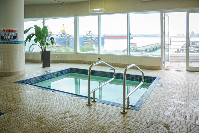 Spacious living room with large windows offering a stunning city view and waterfront access. - 912 - 175 Victory Ship Way, North Vancouver