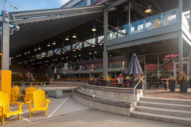 Spacious outdoor patio with yellow Adirondack chairs and modern seating, perfect for relaxing. - 912 - 175 Victory Ship Way, North Vancouver