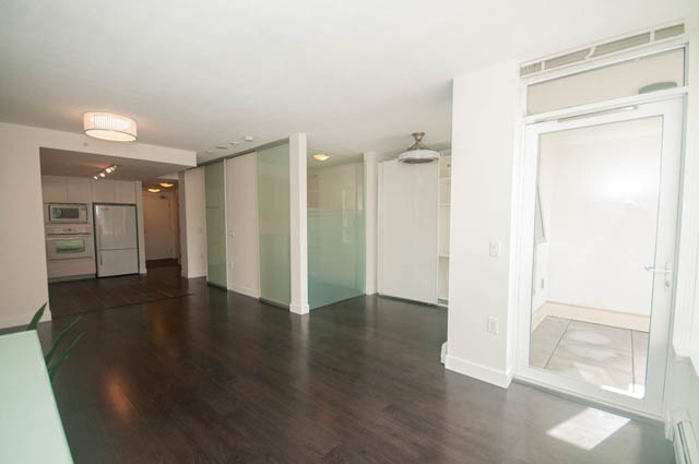 Bright kitchen with hardwood floors and sliding glass doors leading to a balcony. - 103 - 175 West 2nd, North Vancouver