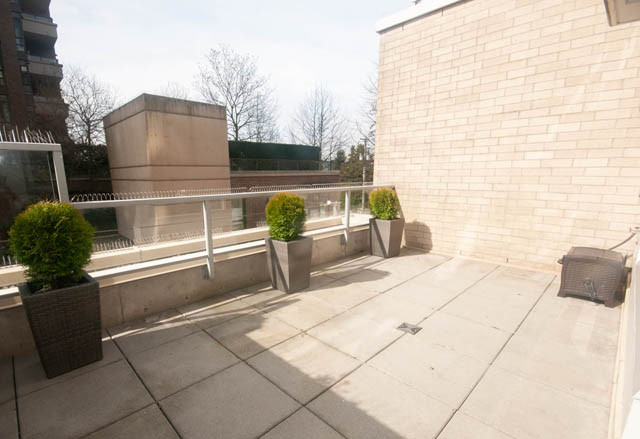 Furnished patio with stone flooring, potted plants, and modern railings. - 103 - 175 West 2nd, North Vancouver