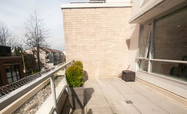 Furnished balcony with modern railings and greenery, offering a serene outdoor space. - 103 - 175 West 2nd, North Vancouver