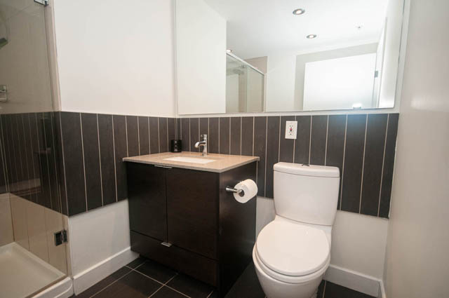 Furnished 1-bedroom bathroom with dark wood paneling and modern fixtures. - 103 - 175 West 2nd, North Vancouver