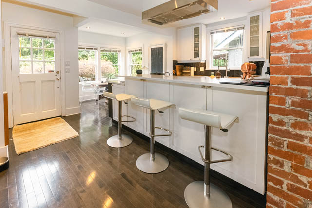 Bright kitchen with white cabinetry, black countertops, and modern bar stools. - 4678 West 9th Ave, Vancouver West Side