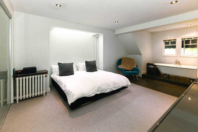 Spacious bedroom with a large bed, modern chair, and clawfoot tub. - 4678 West 9th Ave, Vancouver West Side