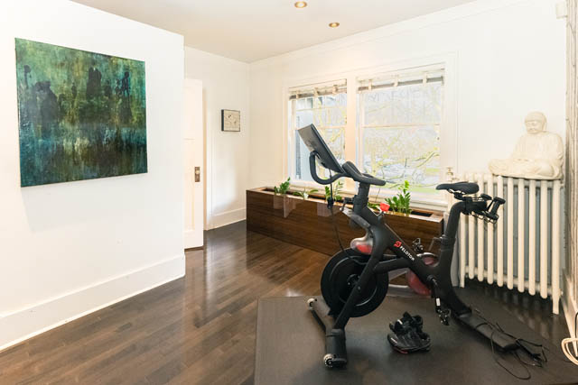 Spacious home gym with hardwood floors, a Peloton bike, and a serene Buddha statue. - 4678 West 9th Ave, Vancouver West Side