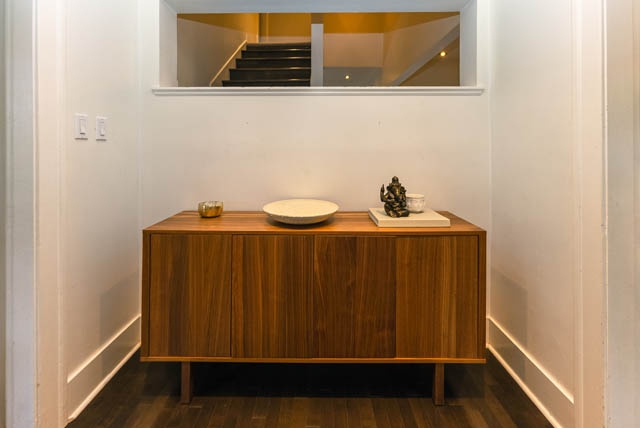 Foyer with wooden sideboard, white walls, and a glimpse of the staircase above. - 4678 West 9th Ave, Vancouver West Side