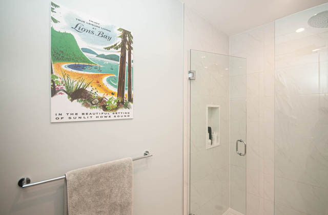 Bright bathroom with modern shower and framed artwork of Lions Bay. - 211 - 733 E 3rd St, North Vancouver