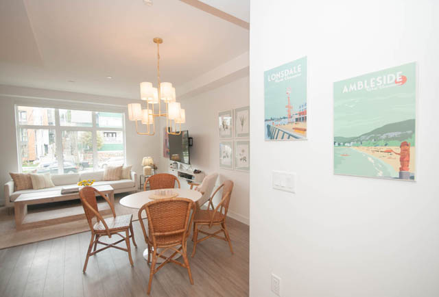 Furnished living room with hardwood floors, city view, and modern chandelier. - 211 - 733 E 3rd St, North Vancouver