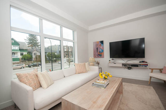 Bright living room with large windows, city view, and modern furniture. - 211 - 733 E 3rd St, North Vancouver
