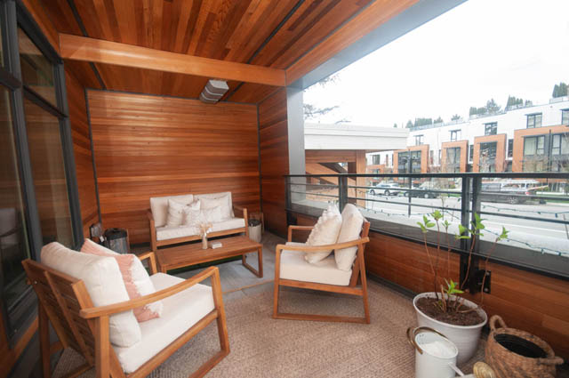 Furnished living room with wooden walls, city view, and comfortable seating. - 211 - 733 E 3rd St, North Vancouver