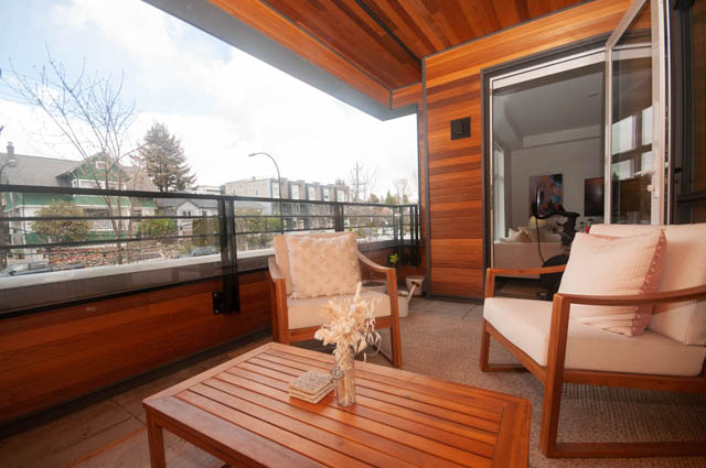 Furnished balcony with wooden furniture and city view. - 211 - 733 E 3rd St, North Vancouver