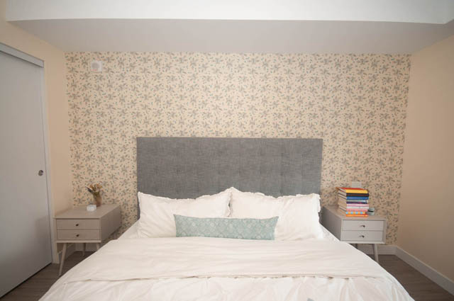 Furnished 1-bedroom + den with floral wallpaper and modern headboard. - 211 - 733 E 3rd St, North Vancouver