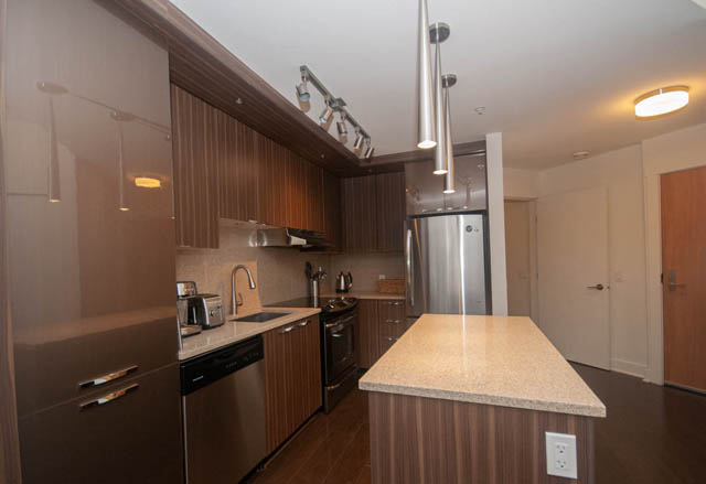 Bright kitchen with granite countertops, stainless steel appliances, and hardwood floors. - 211 - 733 West 14th, North Vancouver