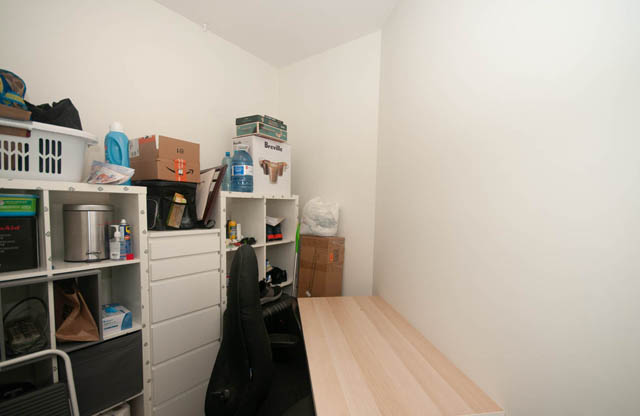 Small, cluttered storage room with white shelves and various items stored. - 211 - 733 West 14th, North Vancouver