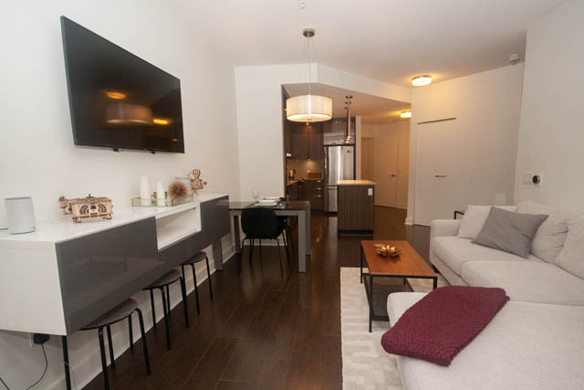 Furnished living room with white couch, hardwood floors, and modern decor. - 211 - 733 West 14th, North Vancouver