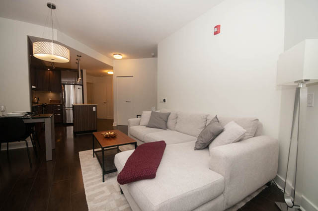 Furnished living room with white couches, hardwood floors, and modern lighting. - 211 - 733 West 14th, North Vancouver