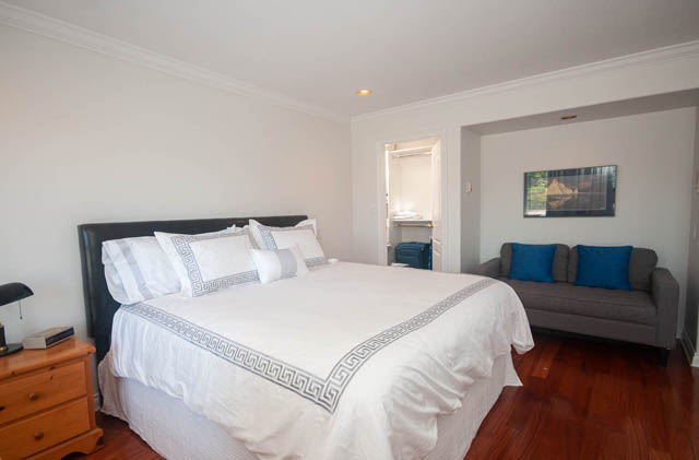 Spacious bedroom with white walls, wooden floors, and a neatly made bed. - Upper  - 2318 West 14th Ave, Vancouver West Side