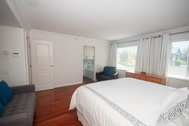 Spacious bedroom with large windows, hardwood floors, and a cozy bed setup. - Upper  - 2318 West 14th Ave, Vancouver West Side