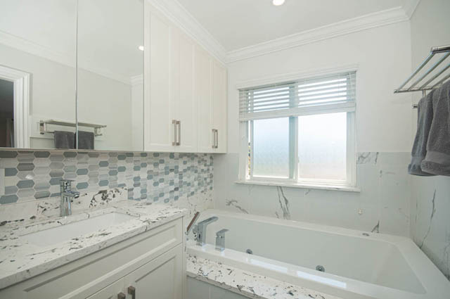 Bright bathroom with marble countertops and hexagonal tile backsplash. - Upper  - 2318 West 14th Ave, Vancouver West Side