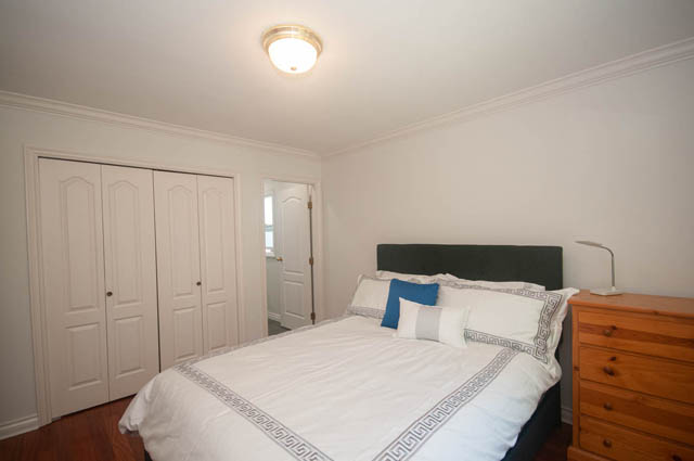 Spacious bedroom with wooden floors, neatly made bed, and built-in closet. - Upper  - 2318 West 14th Ave, Vancouver West Side