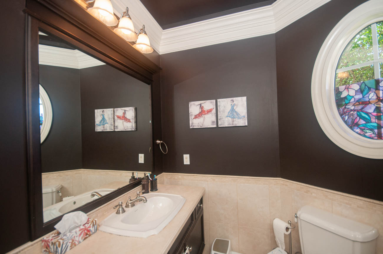 Furnished bathroom with dark walls, light countertop, and stained glass window. - 3440 Wellington Crescent, North Vancouver