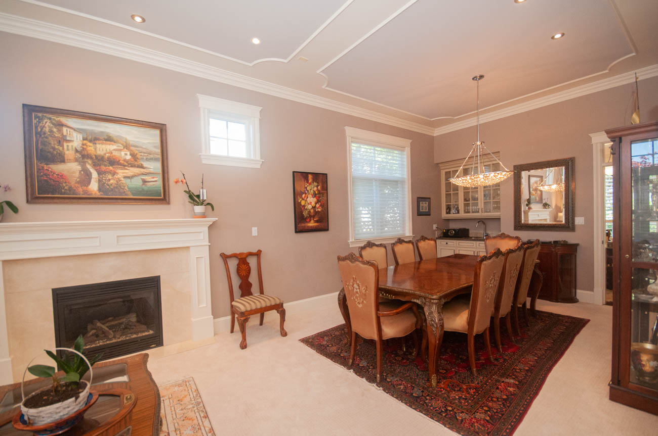 Formal dining room with ornate chandelier, wooden table, and floral paintings. - 3440 Wellington Crescent, North Vancouver