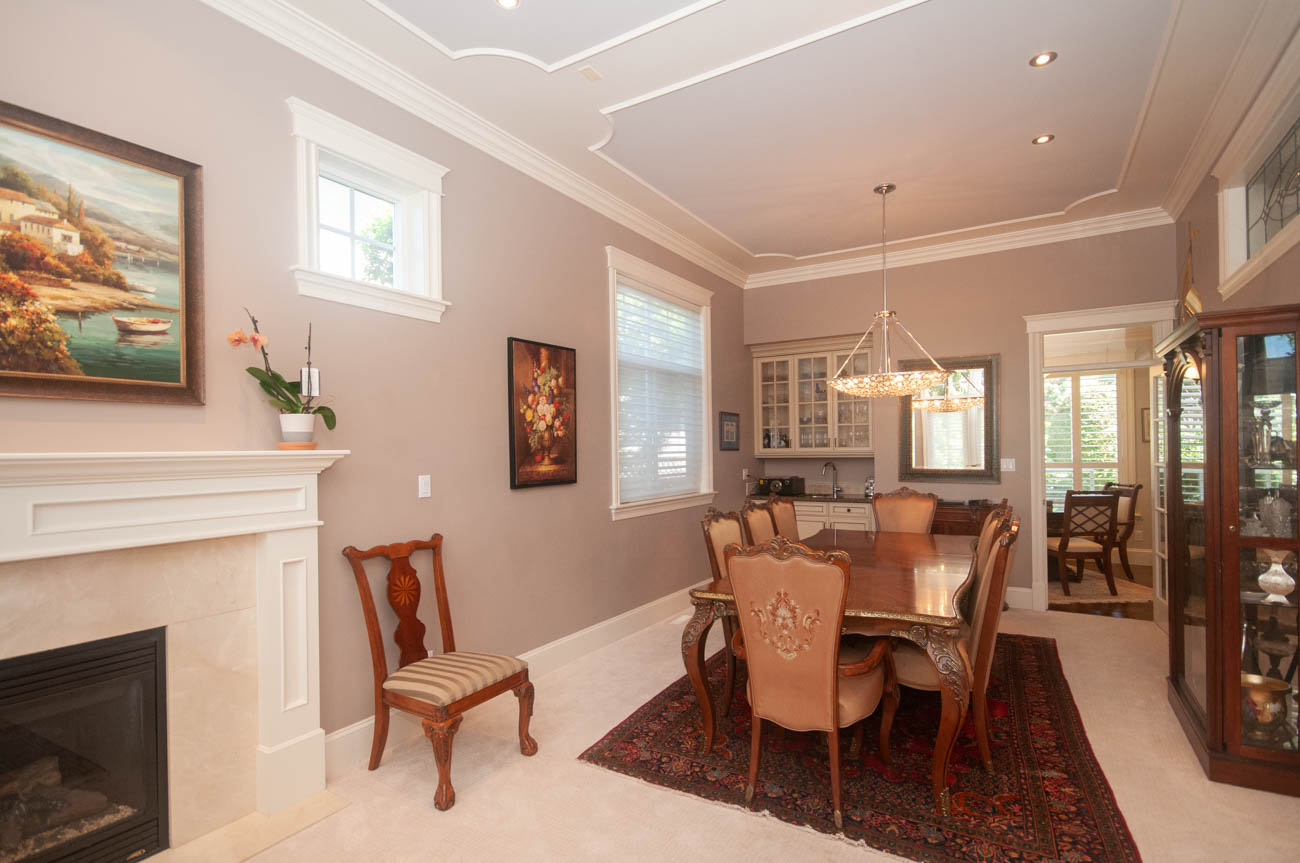 Formal dining room with ornate chandelier, hardwood floors, and a fireplace. - 3440 Wellington Crescent, North Vancouver