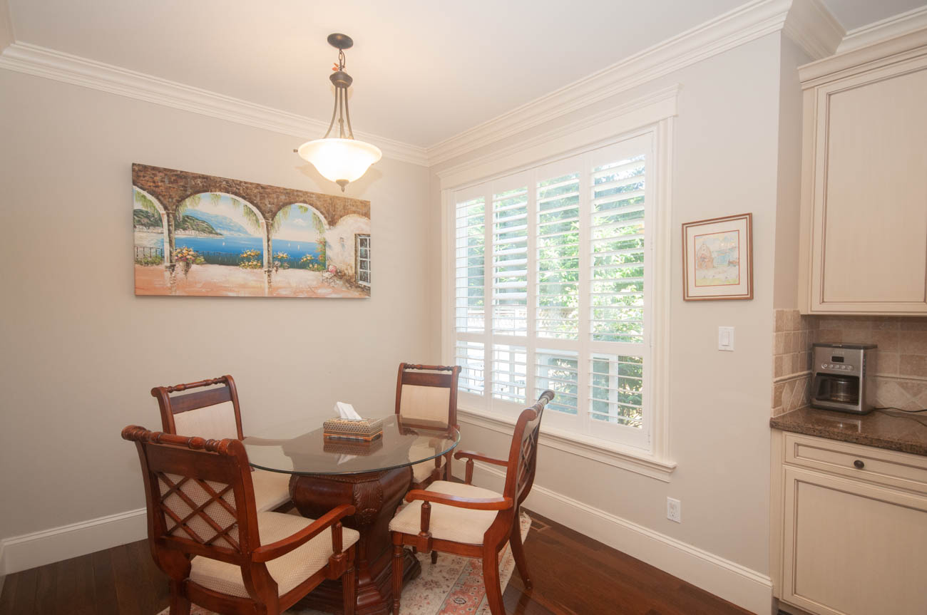 Furnished dining area with hardwood floors, a glass-top table, and a cityscape painting. - 3440 Wellington Crescent, North Vancouver