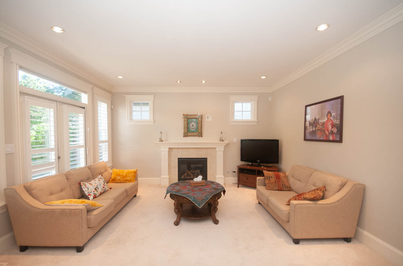 Spacious living room with beige furniture, fireplace, and large windows. - 3440 Wellington Crescent, North Vancouver