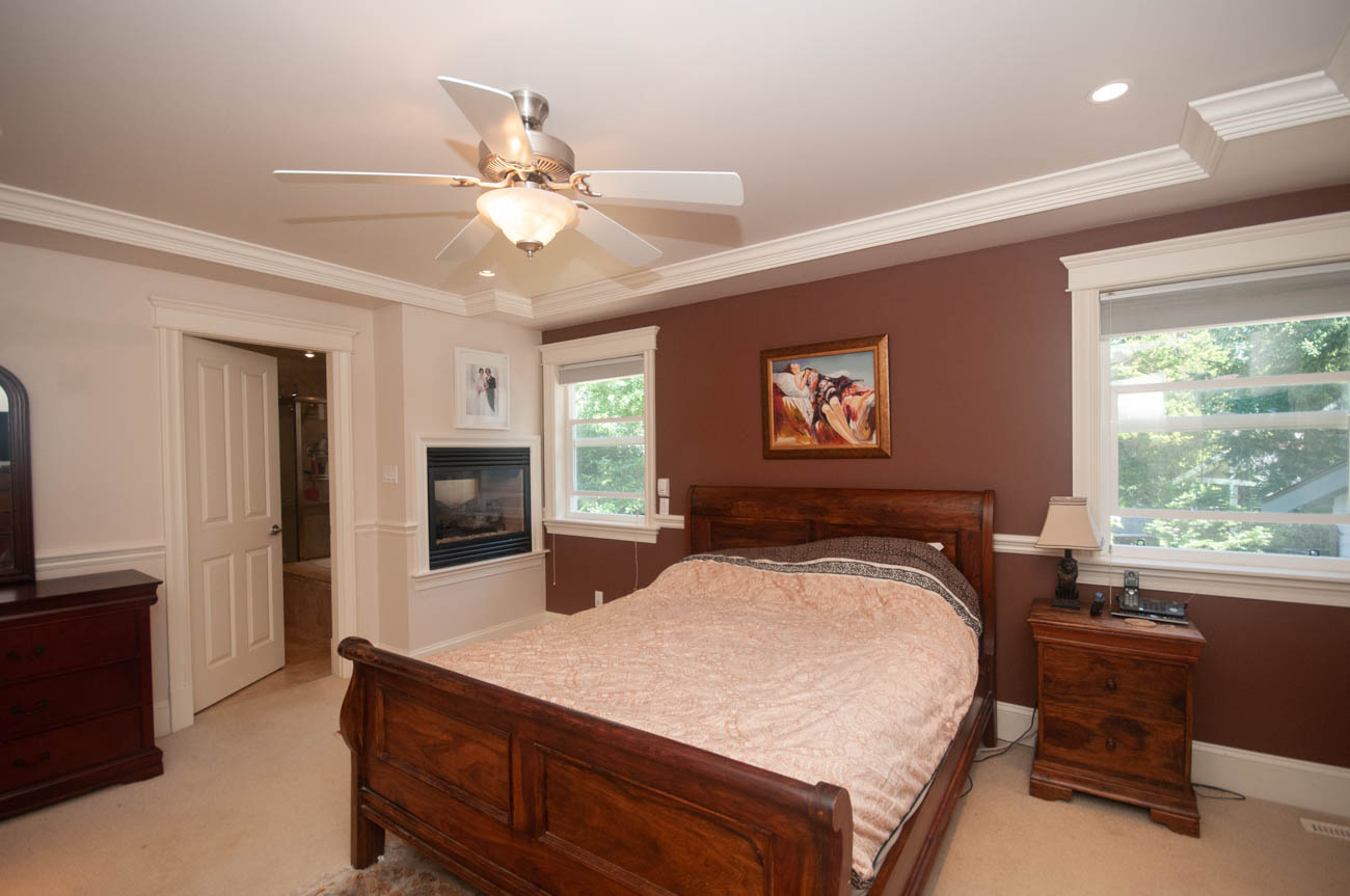 Spacious bedroom with wooden furniture, fireplace, and large windows. - 3440 Wellington Crescent, North Vancouver