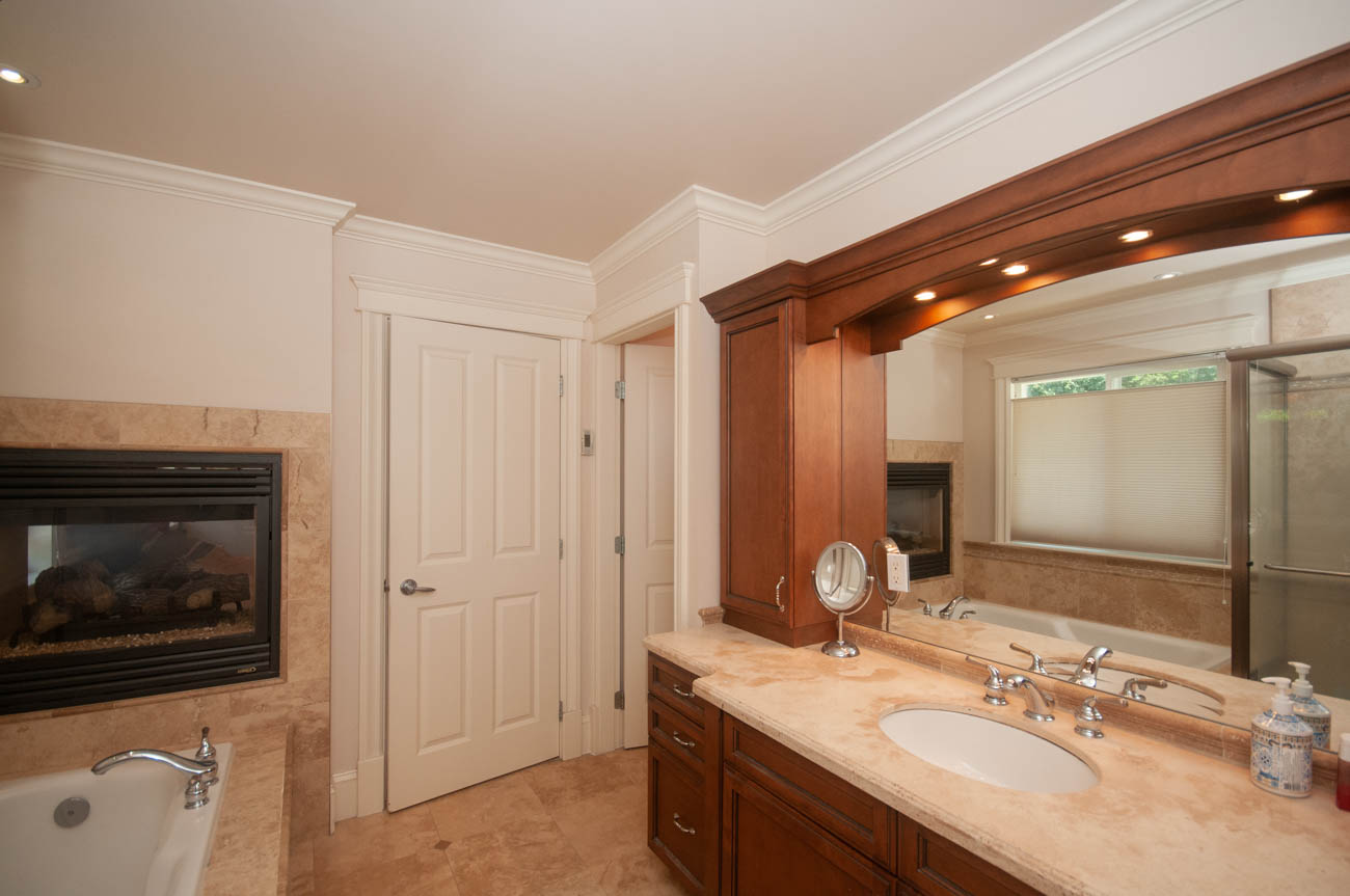 Spacious bathroom with dual sinks, marble countertops, and a fireplace. - 3440 Wellington Crescent, North Vancouver