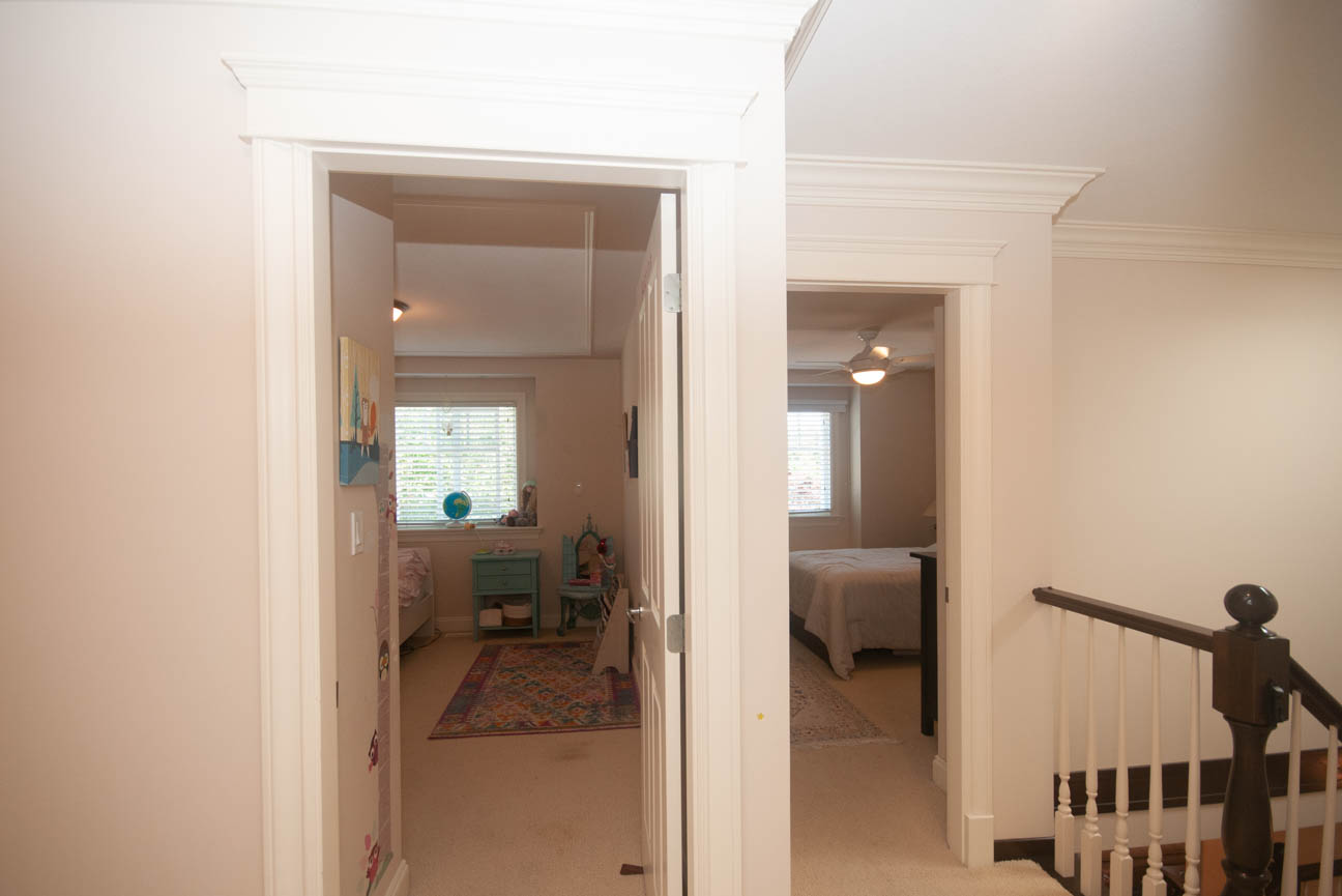 Furnished bedroom with carpeted floor and wooden staircase leading to upper level. - 3440 Wellington Crescent, North Vancouver