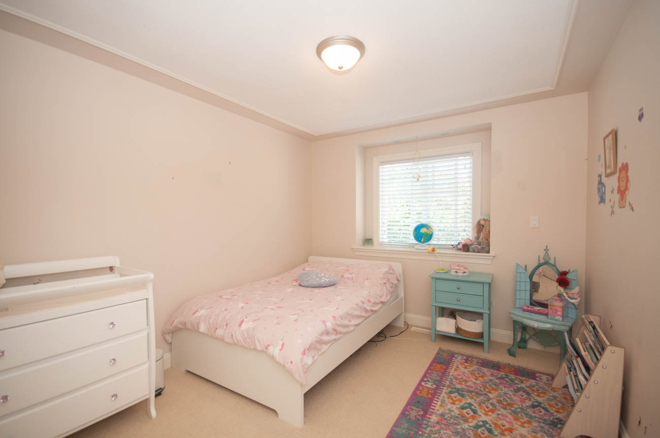 Bright bedroom with twin beds, pastel decor, and a colorful rug. - 3440 Wellington Crescent, North Vancouver