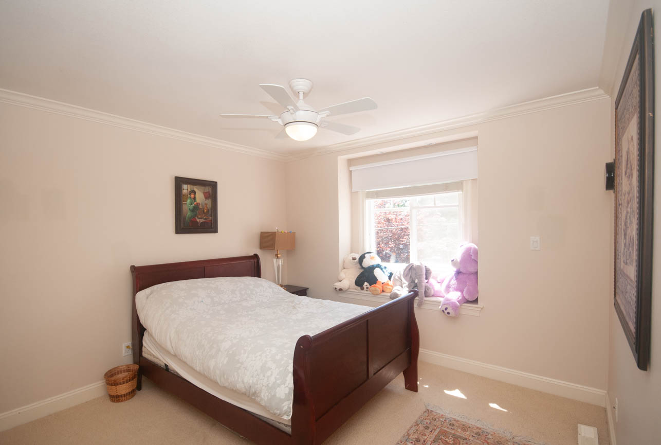 Bright bedroom with twin beds, plush toys, and a ceiling fan. - 3440 Wellington Crescent, North Vancouver